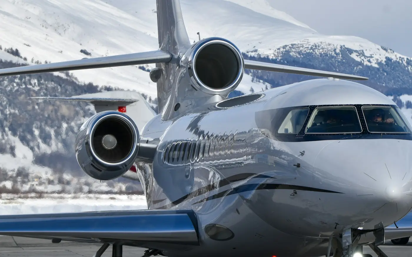 Un jet privé argenté roulant au pied de montagnes enneigées