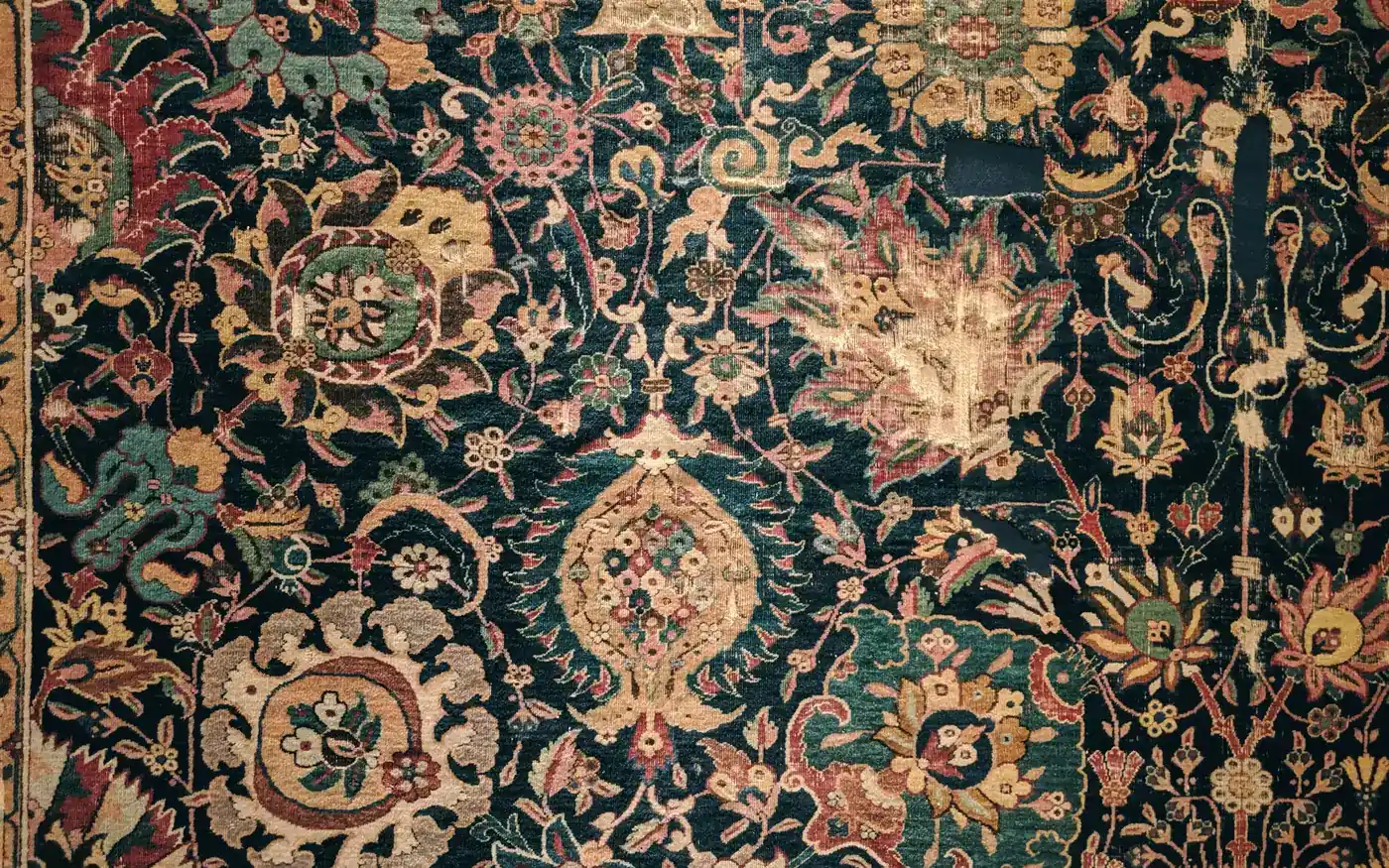 Un tapis ancien vert nuit tissé de fleurs dorées et rosées