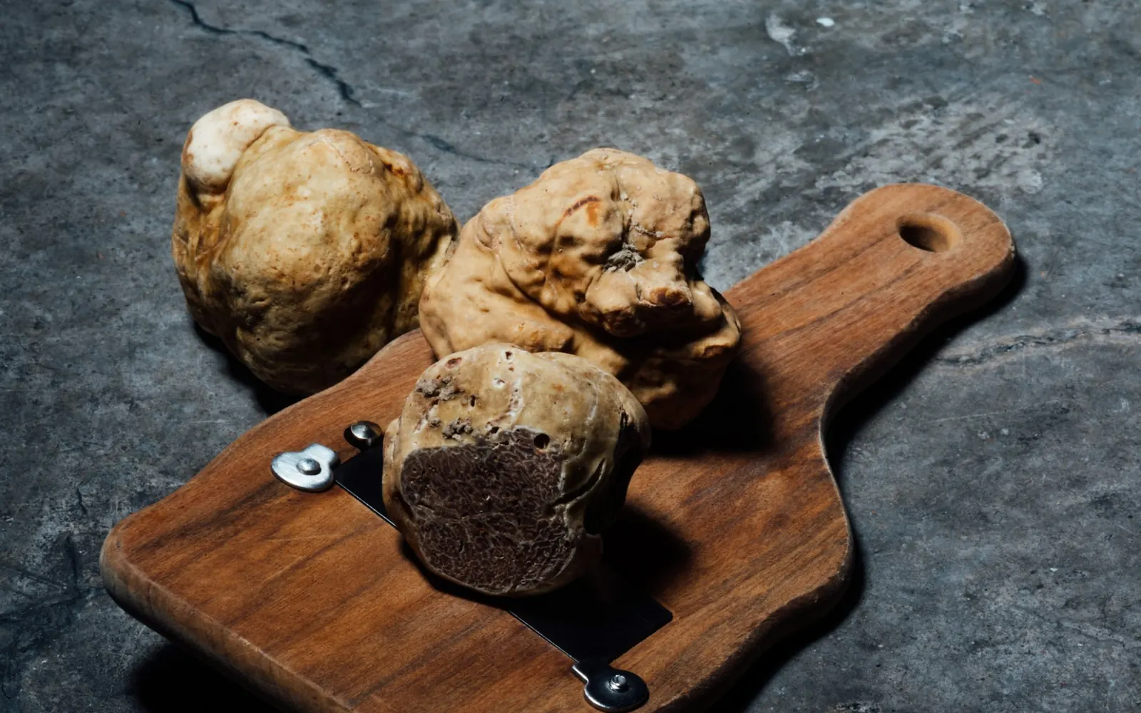 Des truffes blanches entières sur une planche en bois avec une mandoline